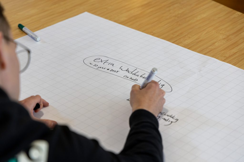 Vel papier ligt op tafel, iemand schrijft op het papier